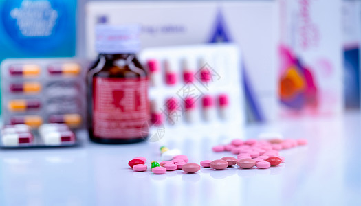 抗病毒物质模糊药瓶上的片剂和胶囊丸泡罩包装中的胶囊和药物纸盒包装上的粉红色和片剂药房柜台上的绿黄色胶囊制药业绿色抗生素药品背景