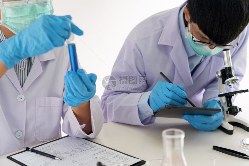 显微镜参加实验室大衣和安全护目镜的有吸引力年轻科学家小组利用实验室中的测试管分析验或调查在实室中分析试或调查研究员助手图片