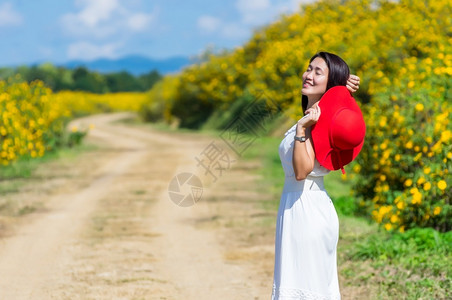 莫负春光南邦红色的一位身着白裙子戴红帽的美丽女在一条农村公路上春光时戴着红帽墨西哥向日葵田MeeMohCoalMine自然背景