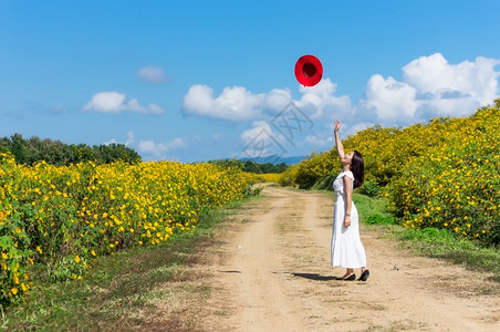 莫负春光一位身着白裙子戴红帽的美丽女在一条农村公路上春光时戴着红帽墨西哥向日葵田MeeMohCoalMine女孩季节放松背景