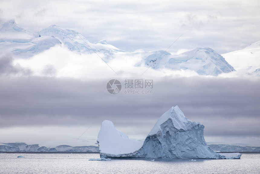 冷静的阴沉典型南极洲大冰山在云墙前穿过平静的海面稀有图片
