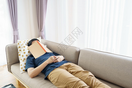 亚洲英俊男子读书而沉睡时看人封面漂浮导致睡眠适当的概念光泽卧室内的图片