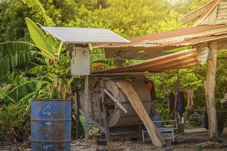 农村住宅区的太阳能电池板和旧石油桶已准备好对泰国农用工业产和家庭住户的工业进行再循环泰国农村风格替代能源概念老的系统屋图片