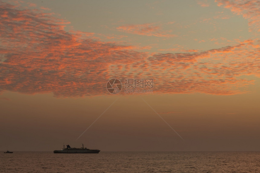 夜晚海洋一艘船在地平线上航行光辉多彩的日落天空平静低潮海滨环境图片