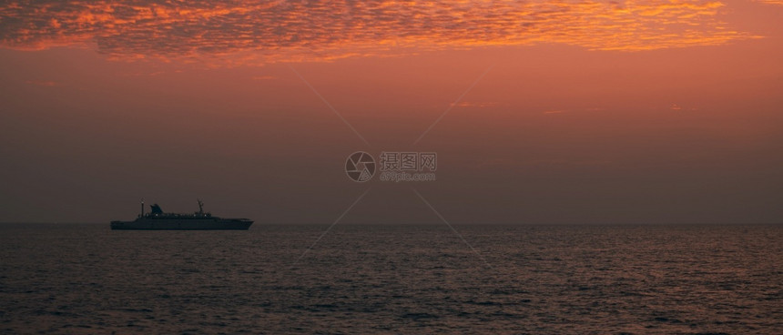 浪潮加勒一艘船在地平线上航行光辉多彩的日落天空平静低潮海滨冷静的图片