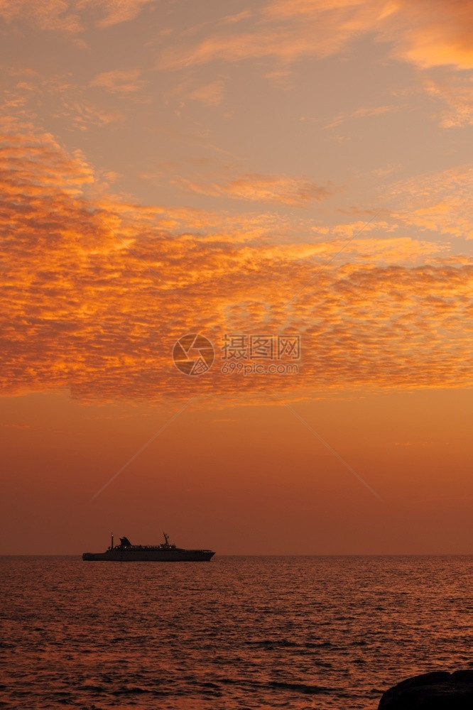 冷静的血管金一艘船在地平线上航行光辉多彩的日落天空平静低潮海滨图片