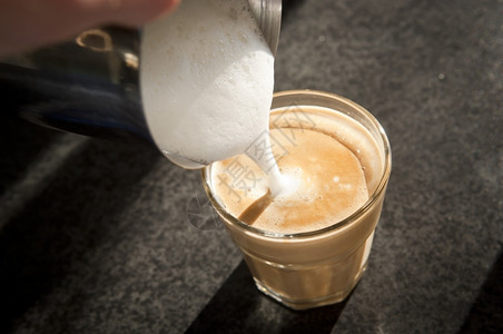 浇注泡沫牛奶从上面倒入现代拿铁玻璃杯茶点图片