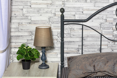 内部的架子床棕色调一个绿花盆张优雅的旧桌灯在床边子上与旧木板灰墙的保持良好平静的面条风格和卧室头板的内部以木板为背景而卧室的头板背景