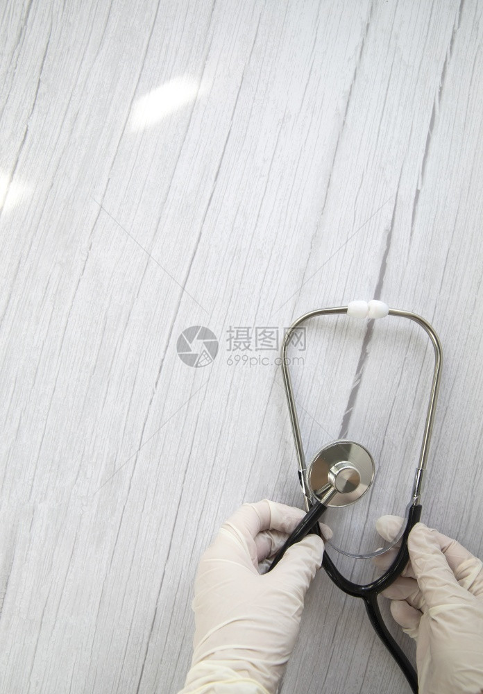 一种商业白色防护医用手套在白色木质背景上拿着听诊器概念访问医生治疗诊断医生横幅平躺顶视图复制空间医院图片