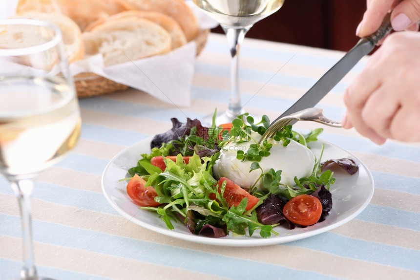 服务切片菜肴一份健康的沙拉由生菜叶蔬混合绿色部分青菜番茄萝卜芽西红柿萝卜芽和奶油酪橄榄和新鲜面包以及一杯白葡萄酒制成图片