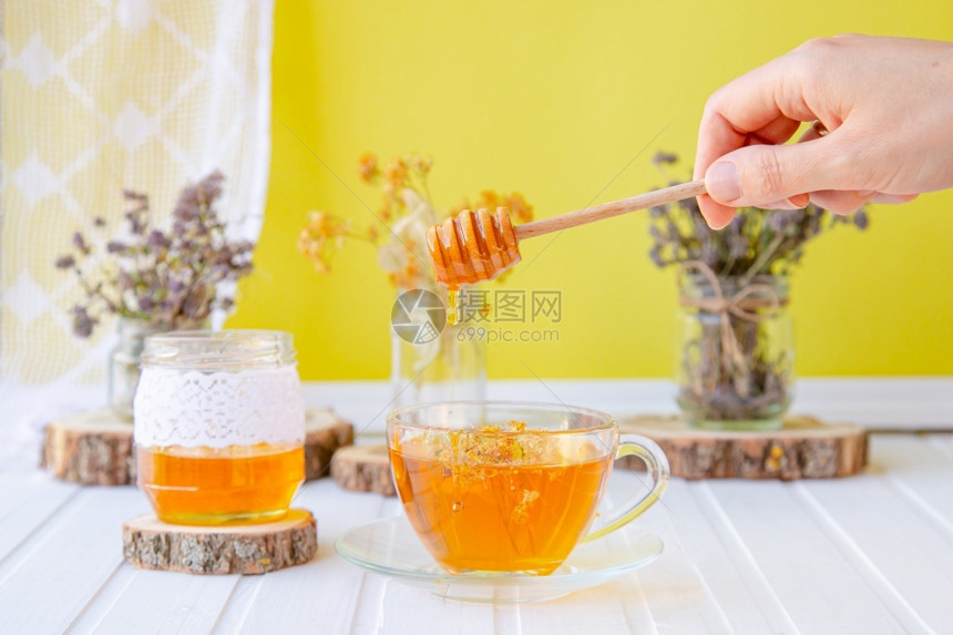 增加凉爽季节的免疫增加清洁有机草药中的茶杯和白木桌上的蜂蜜罐头增加寒冷季节的免疫力增加在天然有机草药中的茶杯和白木桌上的蜂蜜罐素图片
