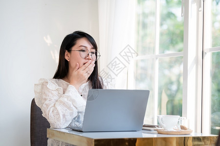 员工女孩技术在咖啡店用笔记本电脑咖啡杯和智能手机如背景通信概念等在咖啡店工作之前以礼节的口吻打着她嘴唇诸如背景沟通概念背景图片