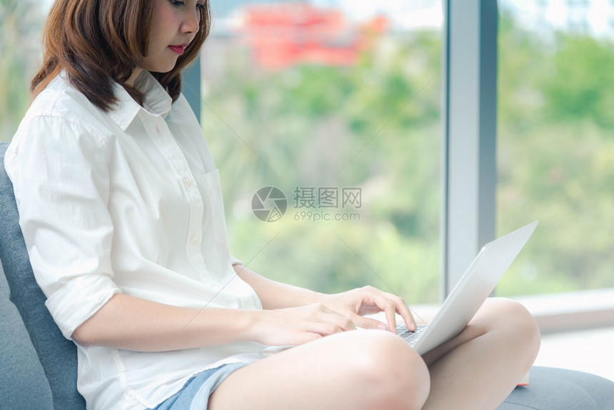 年轻的在职屋家工作参加庭办公室膝上型电脑在线会议的妇女使用笔记本的企业家女商妇坐在沙发技术上新的正常生活方式快乐女人打键盘手提电图片