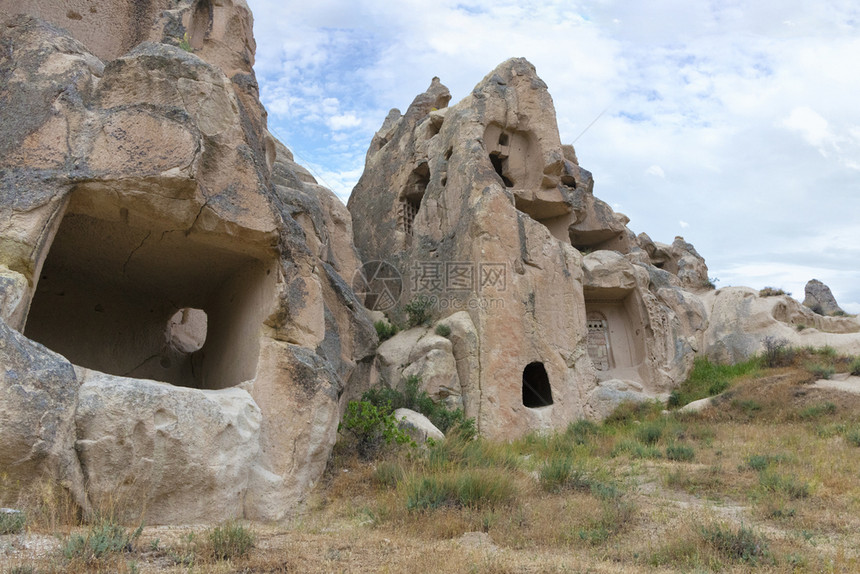 石灰格雷梅结在卡帕多西亚山谷地景观中的古老洞穴与土耳其中部的明蓝和阴云春空相对立在卡帕多西亚红谷古老洞穴中居住图片