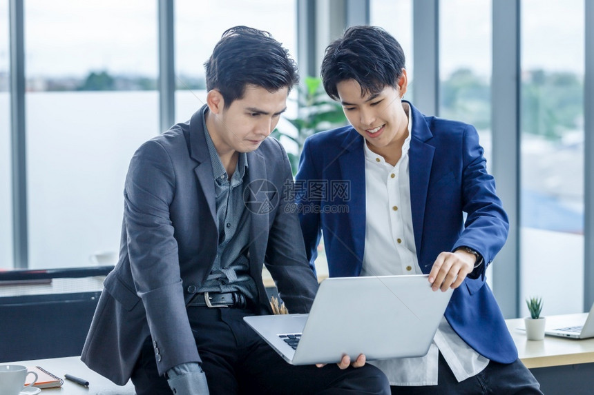 男人尽管快乐的亚洲青年商人公司辅导私秘书助理男女双和变者伙伴同时与笔记本电脑和办公室业务战略合作讨论图片
