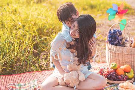 夏天亚洲人小裔男孩骑着超强的妈在草地上野餐时在母亲和儿子一起玩母亲节庆祝并欣赏夏季人与生活方式这个概念的主题背景图片