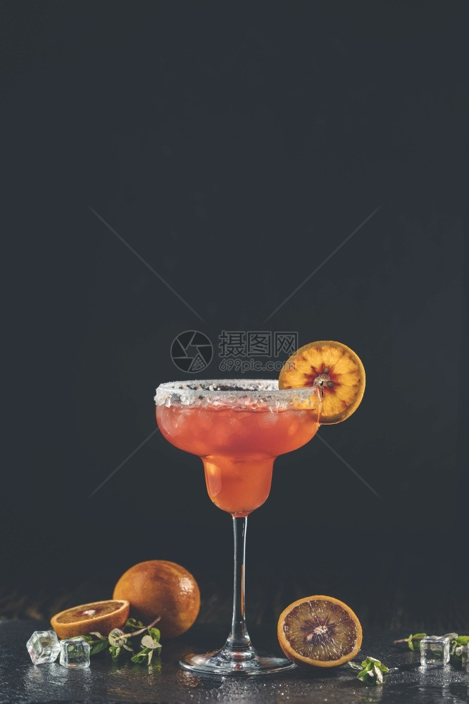 红橙玛格丽塔鸡尾酒加龙舌兰三立秒橙汁压碎的冰和玻璃边缘一些盐装饰在片深浅的露天黑石本底柑橘片上经典的反射桌子图片