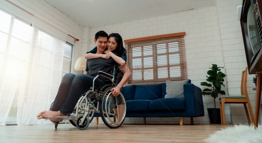 妻子安慰车祸后坐在家中轮椅上的男性图片