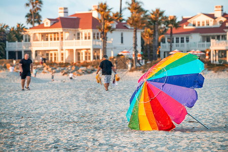 女湿的乐趣日落时带观光游客的多彩海滩雨伞背景图片