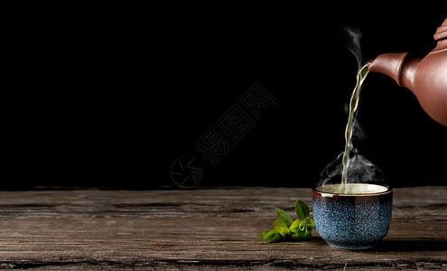 绿色为了菜单热茶从壶倒到蓝碗里古老的木板桌蒸汽在杯子上方茶叶贴在杯子旁边喝完茶礼最低限量主义复制文本空间背景图片
