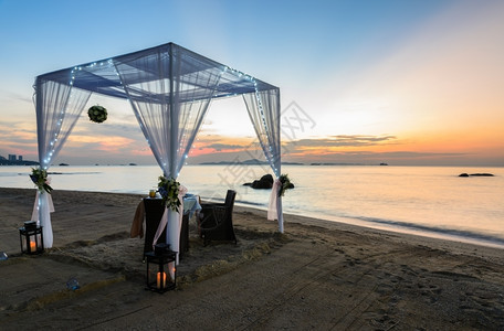 黄昏的热带海滩上白色帐篷的浪漫晚餐桌图片