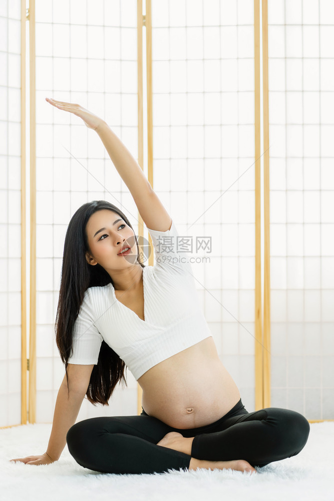 亚洲孕妇在日本风格的房子里坐着和冥想用长毛地毯怀孕锻炼概念做瑜伽练习准备成为健康母亲亚裔孕妇通过坐在和沉睡日本风格的房子里进行瑜图片