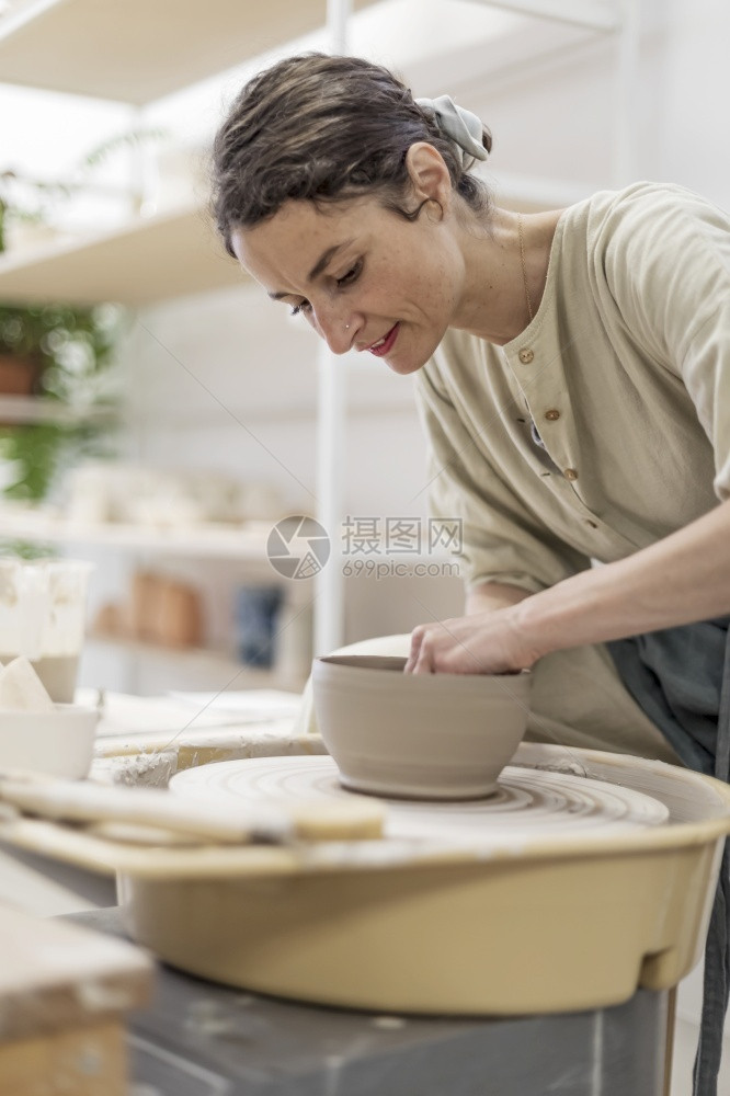 乐器过程形式年轻女子手持陶器刮磨塑女士坐在长凳上用陶轮做罐图片