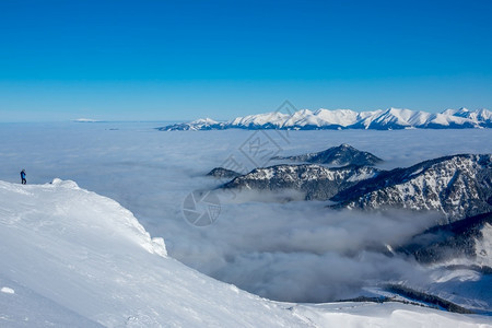 北湖雪雾薄雾风景蓝色天空和雪峰上阳光明媚的天气山谷是浓雾孤独的旅游者拍摄着美丽的白花峰和峡谷中的雾游客最佳背景