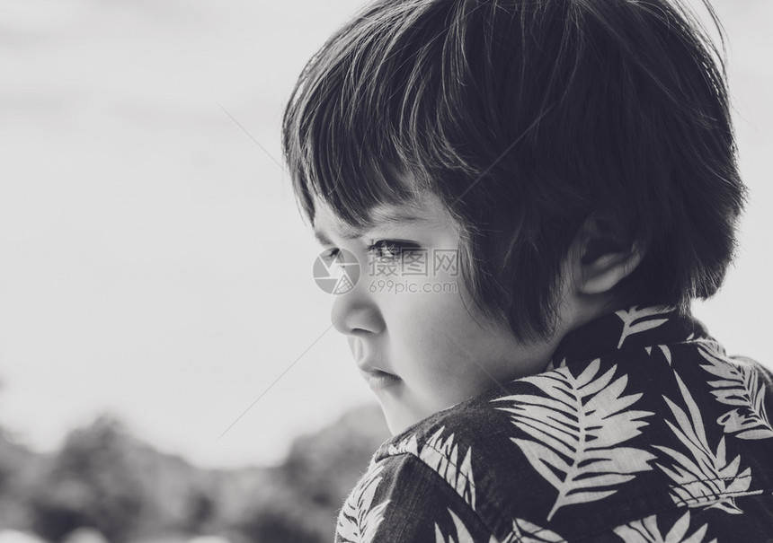 小男孩的情感肖像带着悲伤的脸向下看侧视头部拍摄了孩子的头部无趣脸蛋在阳光明日独自站在公园里孩子深陷其中同时看着Somr的事情独自图片