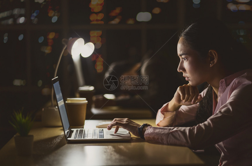 亚洲女商人辛苦地加班工作她的技术笔记本电脑在办公室客户服务和呼叫中心部门勤劳工人和加班她的同事困了低光环境联合办公幸福夜晚图片