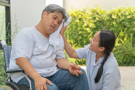 那里中年人和肥胖瘫痪嘴唇手被钉住的和轮椅上利姆软弱有一个妻子用毛巾遮住丈夫的脸充满爱和希望皱巴的四肢背景图片