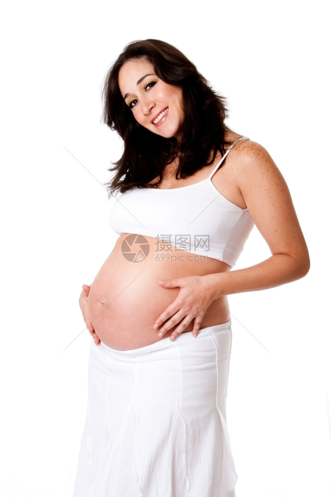 分娩穿着白衣的美丽快乐笑容孕妇抱着她肚子与世隔绝发光的白种人图片