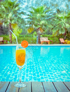 室外游泳池鸡尾酒杯中的橙汁和胡萝卜片夏季热带节日概念服务外部绿松石图片