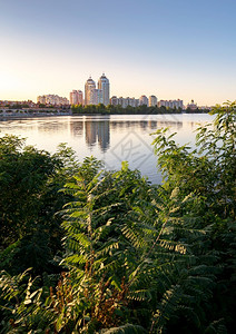 httpswww58各种样的乌克兰基辅Dnieper河附近的高奥波隆建筑乌克兰基辅Dniper河蓝亮的天空和在水中反射各种植物和地表被58皮卡背景
