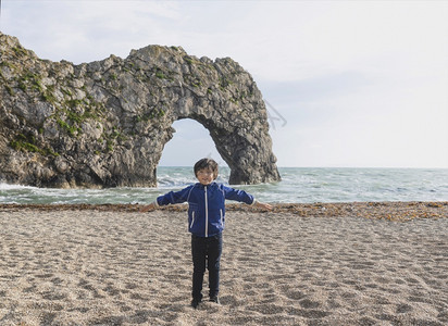 基德隆放松喜悦的男孩在海边带着模糊背景笑站在海边的肖像基德周末在DurdleDoor海滩玩耍联合王国英格兰Dorset中弹杰米太阳背景