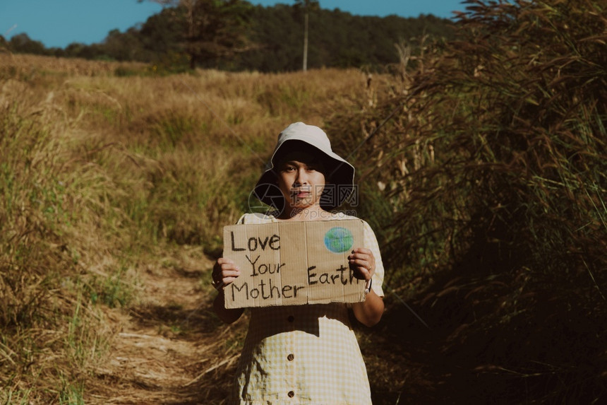 亚洲年轻女生态积极分子站在热带森林里的肖像被摧毁用于种植玉米并用爱你的地球母亲这一字眼张贴海报以换取气候变化的发生照片来源Elo图片