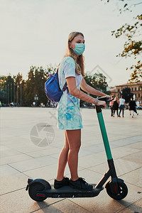 闲暇小工具服务在市中心乘坐电动摩托车的年轻女子戴面罩的妇女避免感染防止疾病在科罗纳毒流行时传播真实刻情况正的时刻来阻止疾病蔓延图片