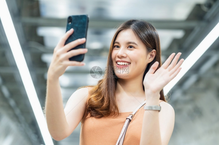 年轻亚洲女乘客使用智能手机进行自拍或电视会议在大城市旅行时与地铁交接的朋友在地铁交汇中谈校友19号放松措施后享受周末假期或者打手图片