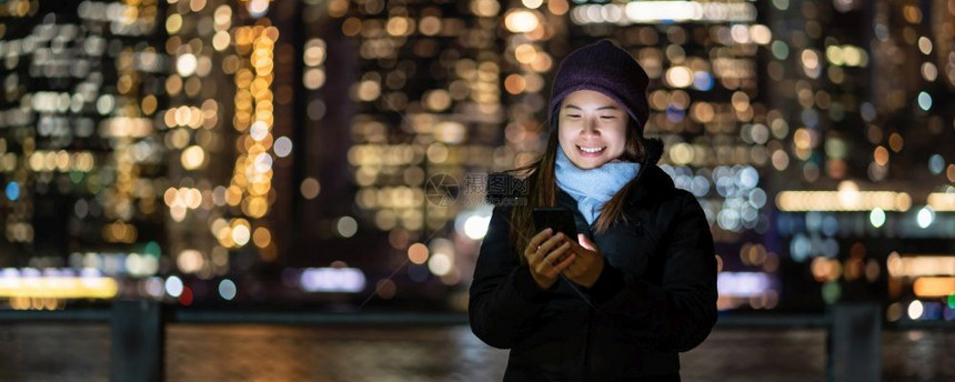 商业电脑以及冬季西装亚裔女封面使用智能手机微笑动作照片模糊的纽约克市风景BOOKH在东河背景旁边美国市区纽约中心城景观图片