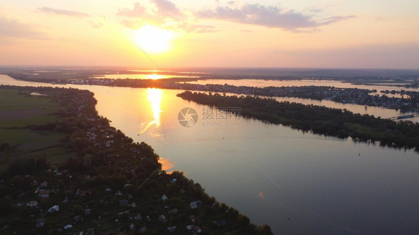 银行农场无人驾驶飞机越由当地村庄包围的摇晃河流周围有各种建筑物和湿地及沼泽生境日落顶风景是共同Reed空中观察的后座户外图片