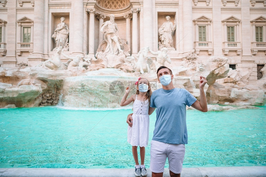 游客雕像爸和小女孩在意大利罗马的特雷维喷泉戴口罩受到危险冠状家庭的保护将硬币扔进喷泉并希望回到喷泉附近的父亲和女儿手里拿着硬币人图片