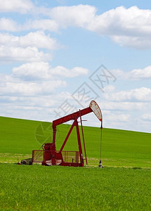 青草沙水库柴油机一个井与泵插孔在行动对抗一个青草的绿色山丘云彩的蓝色天空位于加拿大艾伯塔省一种配重背景
