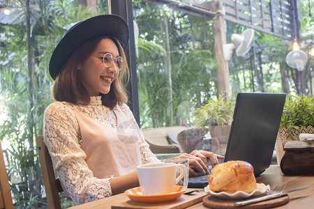 工作晋升在咖啡店用笔记本电脑工作的亚洲女孩吸引人的背景