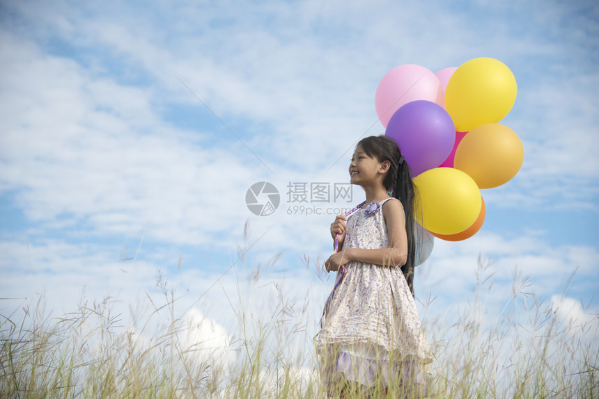 快乐的姑娘在青草地上带着多彩的气球喜悦愉快俏皮图片