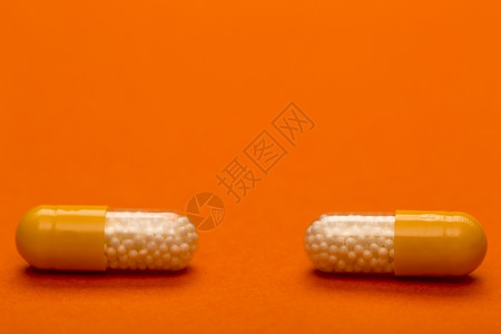 珍珠藕丸止痛药疾病粉红色背景上的彩医用胶囊文本空间带有字的黄色医疗胶囊的设计图片