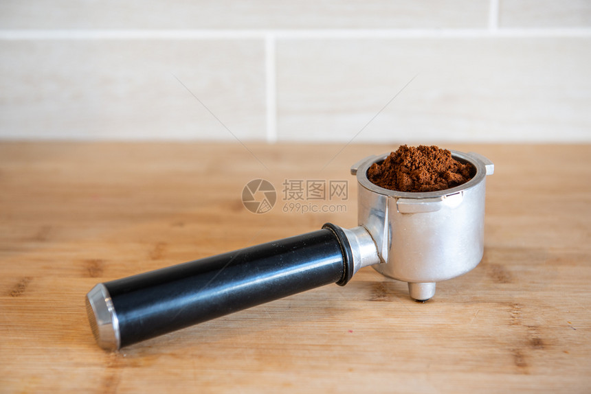 含木制表板上地面咖啡的过滤器持有者与木制表板上地面咖啡的过滤器持有者咖啡因篡改美食图片