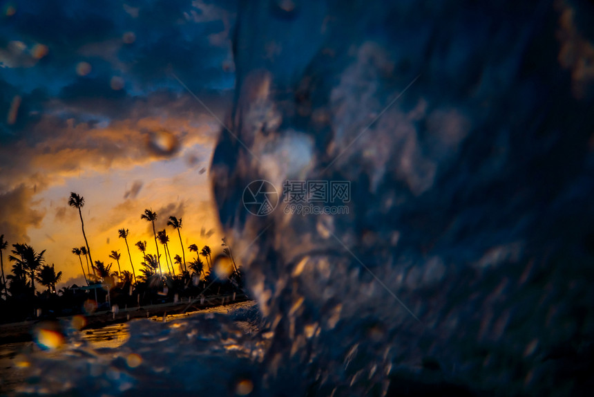 日出早晨步行海浪紧近低角度视野日落在海洋中热带岛屿上拍摄橙色夕阳棕榈树的西尔休特和美丽的多色日落图片