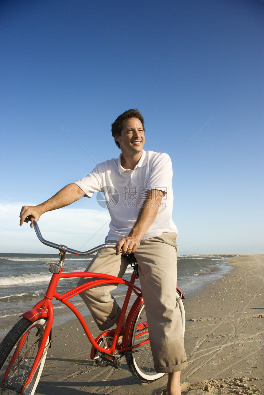 男人骑红色自行车在海滩上图片