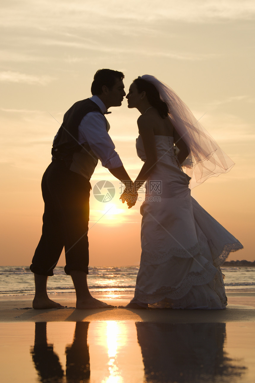 新娘和新郎接吻支撑中年婚礼海岸照片女性两个人日落男子婚姻图片