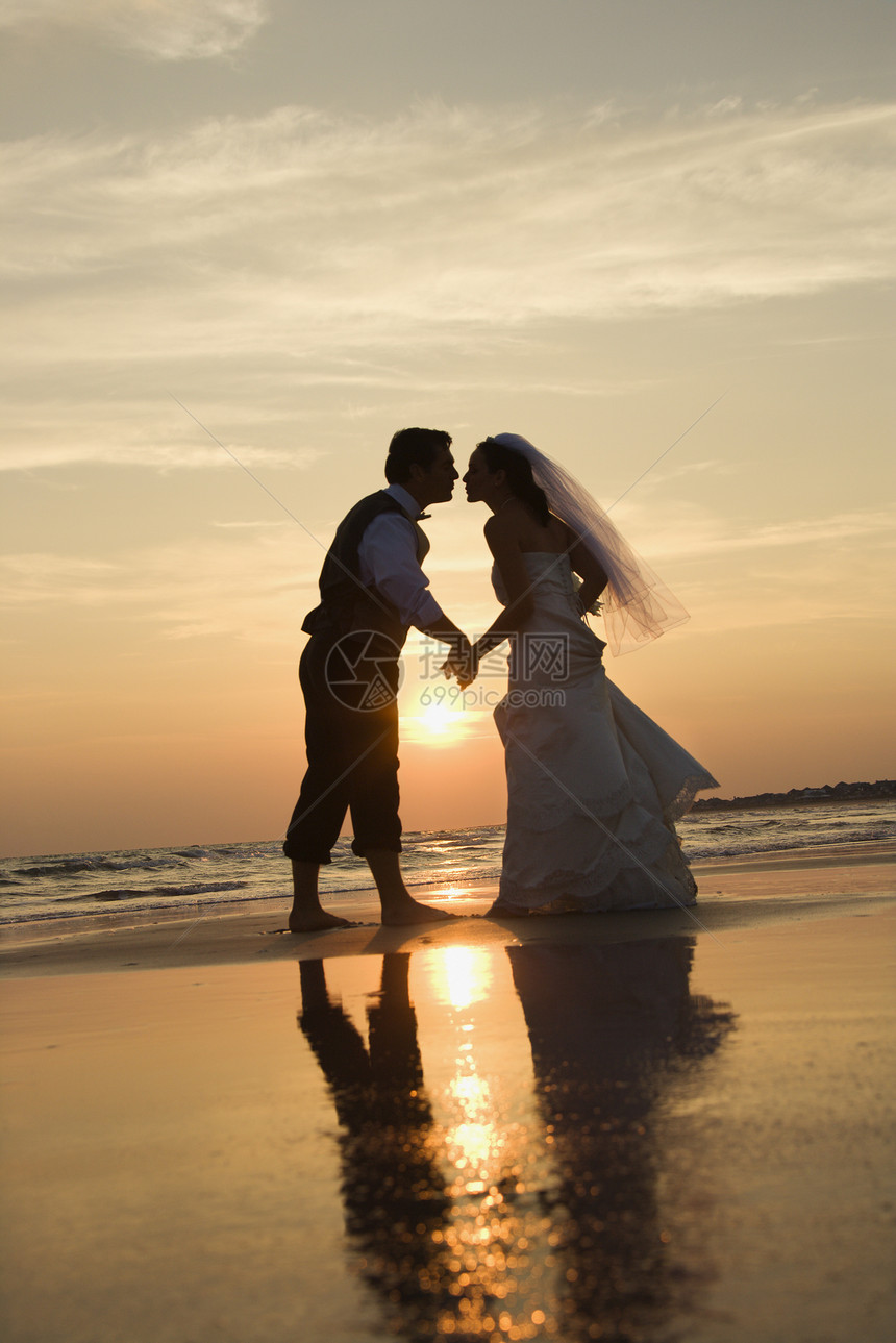 新娘和新郎接吻女性支撑照片日落婚姻婚礼两个人海滩夫妻海岸图片